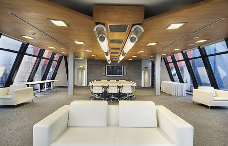 Modern meeting room with a large wooden conference table, ergonomic chairs, natural light, and minimalist decor in a commercial office.